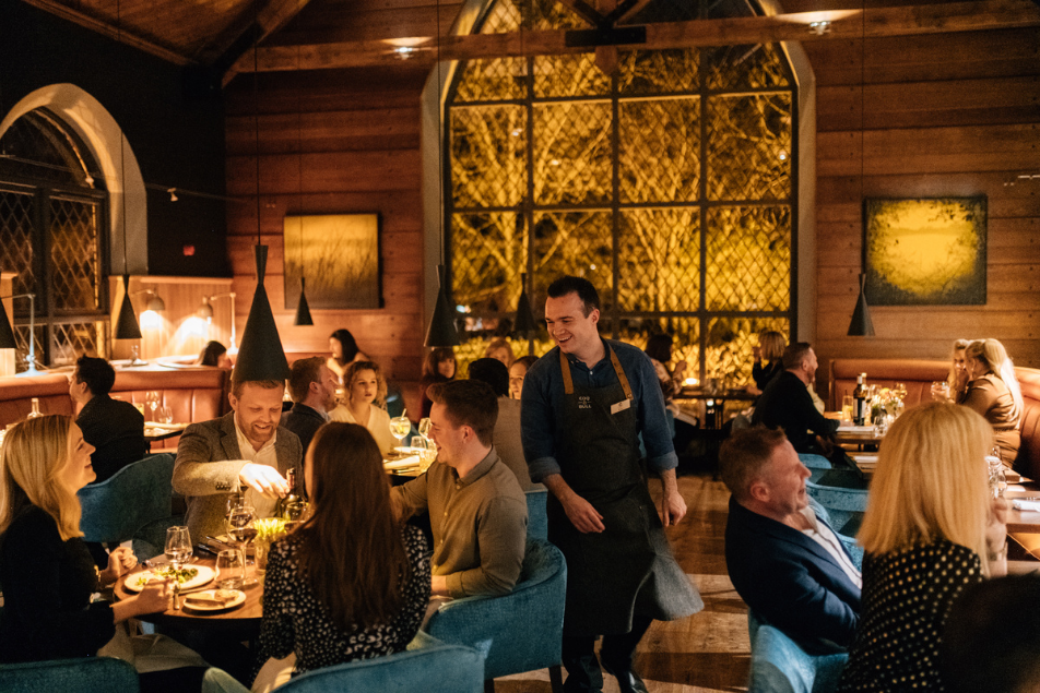 people eating at coq & bull brasserie, staff member smiling at customers