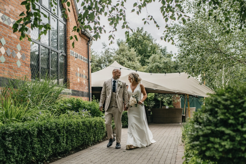 Bride and groom walking through the gardens at Clandeboye Lodge, a woodland wedding venue in Northern Ireland