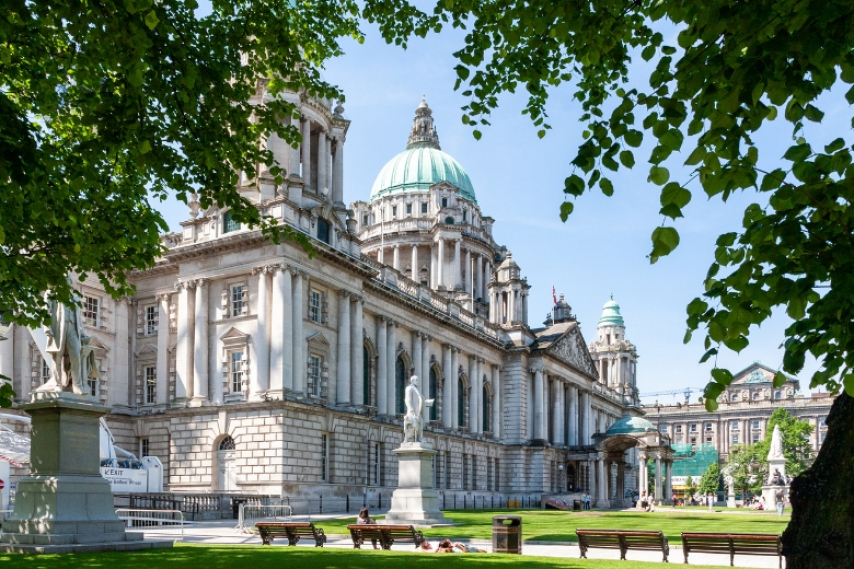 The Belfast City Hall framed by green trees, a landmark to explore among things to do in Northern Ireland.